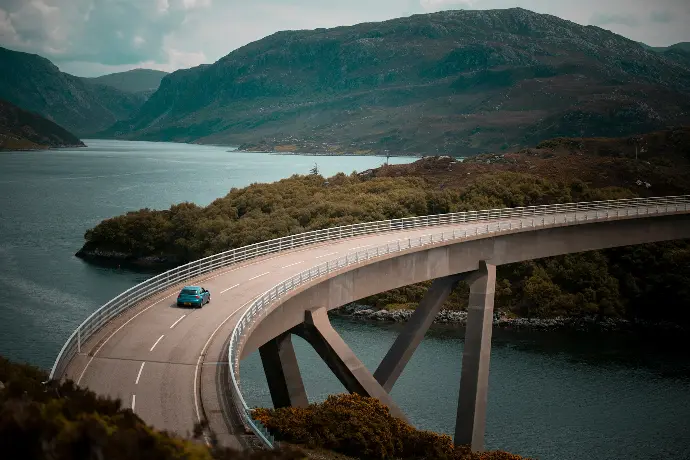 blue vehicle driving on bridge during daytime